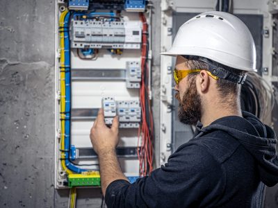 Male electrician at the checkout counter on a blurred background of a switchboard.