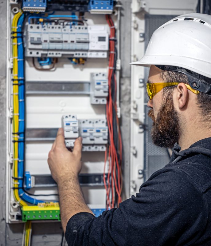 Male electrician at the checkout counter on a blurred background of a switchboard.